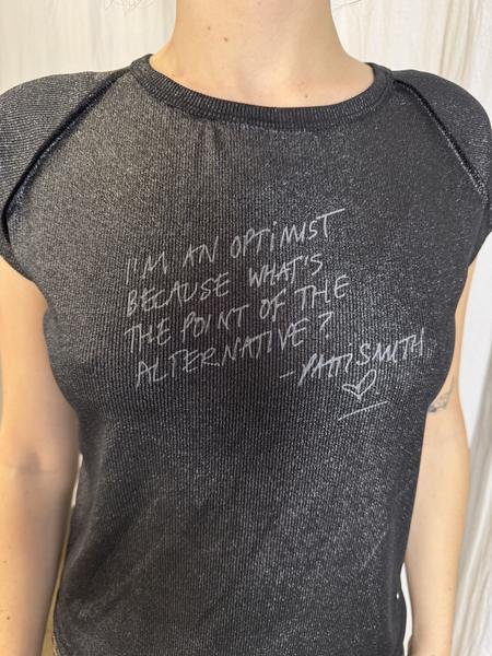 Foto del cliente: la remera negra brillante con frase, de frente, en modelo de calce